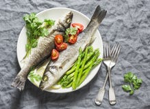 Gebackener Wolfsbarsch mit Spargel und Tomaten Lebensmittelkonzept der gesunden Diät auf einem grauen Hintergrund Lizenzfreie Stockbilder Gebackener Wolfsbarsch mit Spargel und Tomaten Lebensmittelkonzept der gesunden Diät auf einem grauen Hintergrund Lizenzfreie Stockbilder