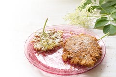 Gebraden elderflower pannekoeken met suikerglazuursuiker op een roze glasschotel stock afbeeldingen Gebraden elderflower pannekoeken met suikerglazuursuiker op een roze glasschotel stock afbeeldingen