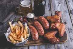 Gebraden kippenvleugels, geroosterde worsten, frieten, noten, witte en rode saus voedsel aan bier stock afbeelding Gebraden kippenvleugels, geroosterde worsten, frieten, noten, witte en rode saus voedsel aan bier stock afbeelding