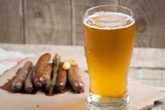 Gebratene Würste und Becher kaltes Bier auf einem Holztisch Beschneidungspfad eingeschlossen lizenzfreie stockfotografie Gebratene Würste und Becher kaltes Bier auf einem Holztisch Beschneidungspfad eingeschlossen lizenzfreie stockfotografie