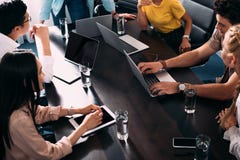 geernteter Schuss von den multikulturellen Teilhabern, die Sitzung bei Tisch mit Laptops in modernem haben lizenzfreie stockbilder geernteter Schuss von den multikulturellen Teilhabern, die Sitzung bei Tisch mit Laptops in modernem haben lizenzfreie stockbilder