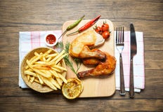 Gegrillte Hühnerbeine auf hölzernem Brett der Platte mit den Pommes-Friteskorbketschuptomaten-Zitronenpaprikas würzig lizenzfreies stockbild Gegrillte Hühnerbeine auf hölzernem Brett der Platte mit den Pommes-Friteskorbketschuptomaten-Zitronenpaprikas würzig lizenzfreies stockbild