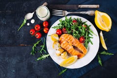 Gegrillte Lachse mit Arugula- und Kirschtomatensalat und -kartoffeln Lizenzfreie Stockbilder Gegrillte Lachse mit Arugula- und Kirschtomatensalat und -kartoffeln Lizenzfreie Stockbilder