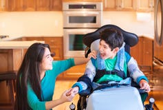 Gehandicapte jongen die in rolstoel met tienerzuster lachen in keuken Stock Foto Gehandicapte jongen die in rolstoel met tienerzuster lachen in keuken Stock Foto