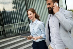 Gehendes nahes Bürogebäude der jungen Geschäftspaare im Freien lizenzfreies stockbild Gehendes nahes Bürogebäude der jungen Geschäftspaare im Freien lizenzfreies stockbild
