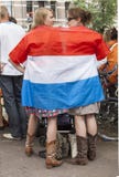 Gekke Nederlandse voetbalventilator in oranje en verpakt in de nationale vlag stock fotografie Gekke Nederlandse voetbalventilator in oranje en verpakt in de nationale vlag stock fotografie