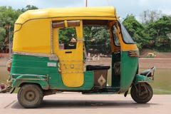 Gele en groene Indische autoriksja Gele en groene tuktuk dichtbij rivier stock foto Gele en groene Indische autoriksja Gele en groene tuktuk dichtbij rivier stock foto
