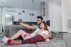 Gelukkig Glimlachend Paar die Selfie-Foto op Cel Slimme Telefoons nemen die op Laag in Moderne Flat, de Jonge Mens en Vrouw zitte royalty-vrije stock foto Gelukkig Glimlachend Paar die Selfie-Foto op Cel Slimme Telefoons nemen die op Laag in Moderne Flat, de Jonge Mens en Vrouw zitte royalty-vrije stock foto