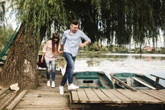 Gelukkig jong paar in openlucht jong liefdepaar die langs handen van een de houten brugholding lopen stock foto Gelukkig jong paar in openlucht jong liefdepaar die langs handen van een de houten brugholding lopen stock foto