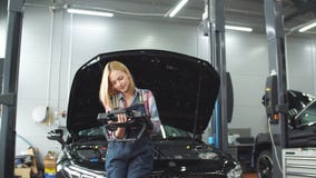 Gelukkig schitterend meisje die computerdiagnostiek gebruiken terwijl het herstellen van auto stock footage Gelukkig schitterend meisje die computerdiagnostiek gebruiken terwijl het herstellen van auto stock footage