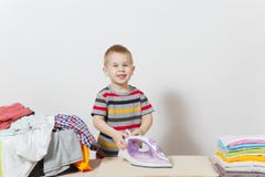 Gelukkig weinig jongen het strijken familiekleding op strijkplank met ijzer Jong geitje die met huishoudelijk werk op witte achte stock afbeelding Gelukkig weinig jongen het strijken familiekleding op strijkplank met ijzer Jong geitje die met huishoudelijk werk op witte achte stock afbeelding