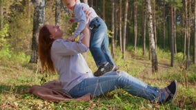Gelukkige familie die op het gazon rusten De moeder met tederheid en liefdespelen met haar kind, de zoon lacht, heeft hij pret ge stock video Gelukkige familie die op het gazon rusten De moeder met tederheid en liefdespelen met haar kind, de zoon lacht, heeft hij pret ge stock video