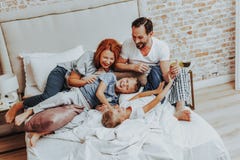 Gelukkige familie die terwijl het spelen samen in bed lachen stock afbeelding Gelukkige familie die terwijl het spelen samen in bed lachen stock afbeelding