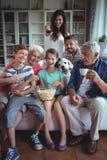 Gelukkige familie het letten op voetbalgelijke van meerdere generaties op televisie in woonkamer stock foto Gelukkige familie het letten op voetbalgelijke van meerdere generaties op televisie in woonkamer stock foto