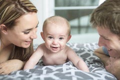Gelukkige familie van vader, moeder en baby het spelen in bed stock fotografie Gelukkige familie van vader, moeder en baby het spelen in bed stock fotografie