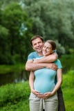 Gelukkige glimlachende knappe mens die zijn mooie zwangere vrouw omhelzen stock afbeelding Gelukkige glimlachende knappe mens die zijn mooie zwangere vrouw omhelzen stock afbeelding