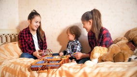 Gelukkige glimlachende oudere meisjes die op bed met peuterjongen spelen stock foto's Gelukkige glimlachende oudere meisjes die op bed met peuterjongen spelen stock foto's