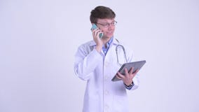 Gelukkige jonge mens arts die op de telefoon spreken en digitale tablet gebruiken stock video Gelukkige jonge mens arts die op de telefoon spreken en digitale tablet gebruiken stock video