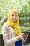 Gelukkige jonge moslimvrouw die een telefoon houden terwijl uit het kijken Stock Foto's Gelukkige jonge moslimvrouw die een telefoon houden terwijl uit het kijken Stock Foto's