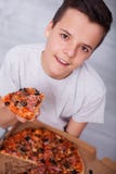 Gelukkige tienerjongen die een gehele doos van pizza hebben allen voor zich royalty-vrije stock afbeelding Gelukkige tienerjongen die een gehele doos van pizza hebben allen voor zich royalty-vrije stock afbeelding