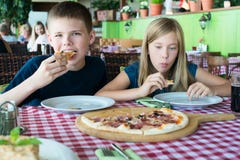 Gelukkige tieners die pizza in een koffie eten Vrienden of siblings die pret in restaurant hebben royalty-vrije stock afbeeldingen Gelukkige tieners die pizza in een koffie eten Vrienden of siblings die pret in restaurant hebben royalty-vrije stock afbeeldingen