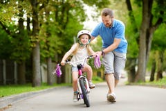 Gelukkige vader die zijn kleine dochter onderwijzen om een fiets te berijden Kind die een fiets leren te berijden stock afbeeldingen Gelukkige vader die zijn kleine dochter onderwijzen om een fiets te berijden Kind die een fiets leren te berijden stock afbeeldingen