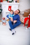Gelukkige vader en zijn zoon thuis dichtbij het Kerstboomspel royalty-vrije stock afbeelding Gelukkige vader en zijn zoon thuis dichtbij het Kerstboomspel royalty-vrije stock afbeelding