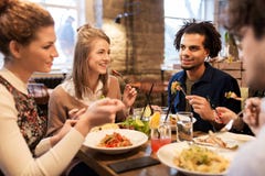 Gelukkige vrienden die en bij restaurant eten drinken stock fotografie Gelukkige vrienden die en bij restaurant eten drinken stock fotografie