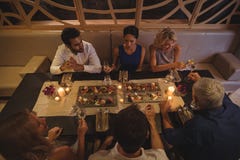 Gelukkige vrienden die met elkaar interactie aangaan terwijl het hebben van diner stock fotografie Gelukkige vrienden die met elkaar interactie aangaan terwijl het hebben van diner stock fotografie