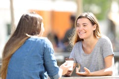 Gelukkige vrouwen die zitting in een park spreken stock foto's Gelukkige vrouwen die zitting in een park spreken stock foto's
