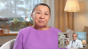 Geneeskunde online Bejaarde die haar arts raadplegen die videopraatje thuis gebruiken stock footage Geneeskunde online Bejaarde die haar arts raadplegen die videopraatje thuis gebruiken stock footage