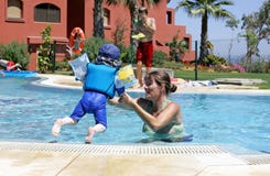 Generi l'aiuto del suo figlio giovane nuotare e saltare in uno swimmin pieno di sole Fotografia Stock Generi l'aiuto del suo figlio giovane nuotare e saltare in uno swimmin pieno di sole Fotografia Stock