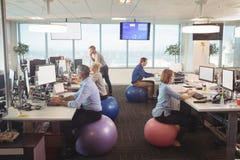 Gens d'affaires travaillant au bureau tout en se reposant sur des boules d'exercice images libres de droits Gens d'affaires travaillant au bureau tout en se reposant sur des boules d'exercice images libres de droits