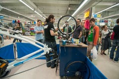 Gente d'istruzione del meccanico come allineare una ruota della bici su un supporto d'allineamento immagine stock Gente d'istruzione del meccanico come allineare una ruota della bici su un supporto d'allineamento immagine stock