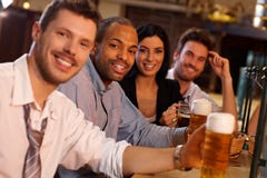Gente joven feliz que se sienta en el pub, cerveza de consumición fotos de archivo Gente joven feliz que se sienta en el pub, cerveza de consumición fotos de archivo