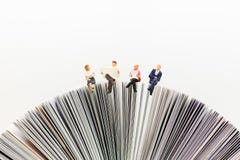 Gente miniatura, gruppo di affari che si siede sul libro, leggendo la carta di notizie, usando come affare del fondo, concetto di fotografia stock libera da diritti Gente miniatura, gruppo di affari che si siede sul libro, leggendo la carta di notizie, usando come affare del fondo, concetto di fotografia stock libera da diritti