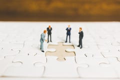 Gente miniatura: Hombre de negocios que se coloca en el rompecabezas imagen de archivo libre de regalías Gente miniatura: Hombre de negocios que se coloca en el rompecabezas imagen de archivo libre de regalías