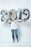 Gentille fille drôle habillée dans le T-shirt blanc, les jeans et les chaussettes roses tenant des ballons sous forme de numéros image libre de droits Gentille fille drôle habillée dans le T-shirt blanc, les jeans et les chaussettes roses tenant des ballons sous forme de numéros image libre de droits