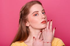 Gentle woman with bright makeup, straight hair with red shade, has manicured hand. Model in yellow shirt, keeps hands near chin, royalty free stock photography Gentle woman with bright makeup, straight hair with red shade, has manicured hand. Model in yellow shirt, keeps hands near chin, royalty free stock photography