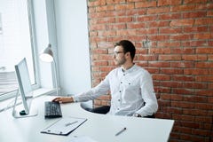Gerente considerável pensativo que olha a janela ao sentar-se na tabela fotografia de stock Gerente considerável pensativo que olha a janela ao sentar-se na tabela fotografia de stock