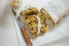 German Christmas stollen with cut off slices on parchment paper, white concrete background, knife, lit candle, top view royalty free stock photos German Christmas stollen with cut off slices on parchment paper, white concrete background, knife, lit candle, top view royalty free stock photos