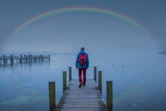 A german man is looking forward on a kay in the middle of the lake in front of a rainbow