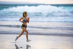 Geschikte en atletische Aziatische Chinese sportieve vrouw die op mooi strand lopen die joggingtraining op zonsondergang in gesch stock afbeeldingen Geschikte en atletische Aziatische Chinese sportieve vrouw die op mooi strand lopen die joggingtraining op zonsondergang in gesch stock afbeeldingen