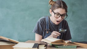 Geschokte student die door een vergrootglas kijken royalty-vrije stock foto Geschokte student die door een vergrootglas kijken royalty-vrije stock foto
