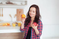 Geschossen von einer dunkelhaarigen kaukasischen Frau, die Äpfel mit Orangen vergleicht Lizenzfreie Stockfotografie Geschossen von einer dunkelhaarigen kaukasischen Frau, die Äpfel mit Orangen vergleicht Lizenzfreie Stockfotografie