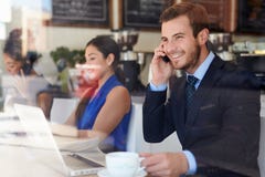Geschäftsmann Using Mobile Phone und Laptop in der Kaffeestube stockfotografie Geschäftsmann Using Mobile Phone und Laptop in der Kaffeestube stockfotografie