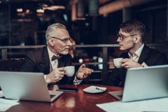 Geschäftsmänner trinken Kaffee und betrachten einander lizenzfreies stockbild Geschäftsmänner trinken Kaffee und betrachten einander lizenzfreies stockbild
