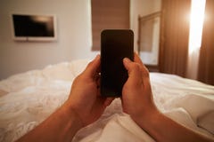 Gesichtspunkt-Bild von Person In Bed Looking At-Handy lizenzfreie stockfotos Gesichtspunkt-Bild von Person In Bed Looking At-Handy lizenzfreie stockfotos