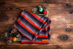Gestrickter Schal in den schwarzen und roten Streifen und in den Weihnachtsdekorationen auf hölzernem Hintergrund stockfotografie Gestrickter Schal in den schwarzen und roten Streifen und in den Weihnachtsdekorationen auf hölzernem Hintergrund stockfotografie