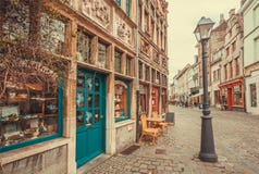 Old street lantern and brick house with reliefs on wall and small store with colorful doors stock photos Old street lantern and brick house with reliefs on wall and small store with colorful doors stock photos